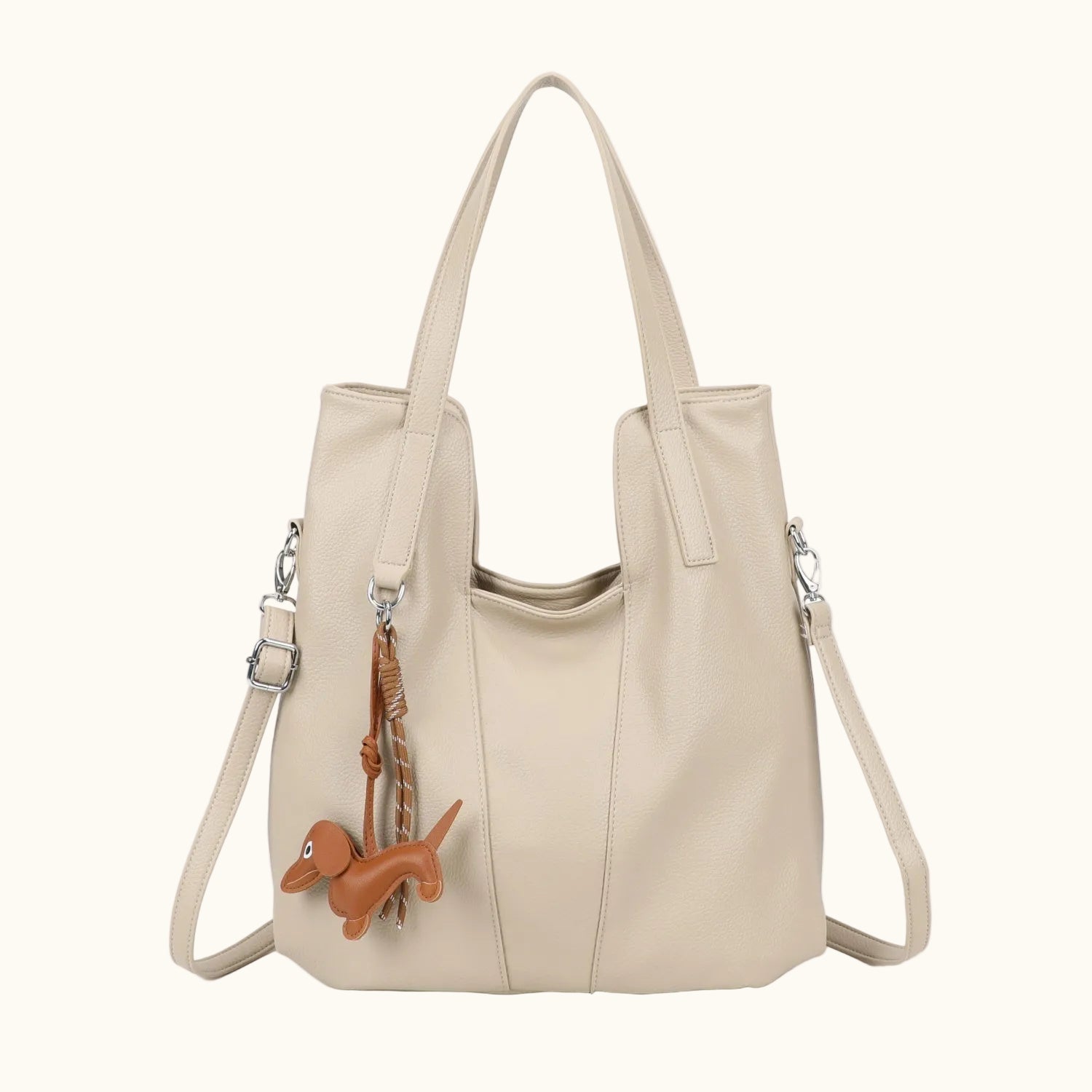 Beige handbag with a small brown dog charm on a white background