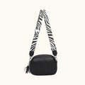 Black camera bag with a zebra-patterned strap on a white background