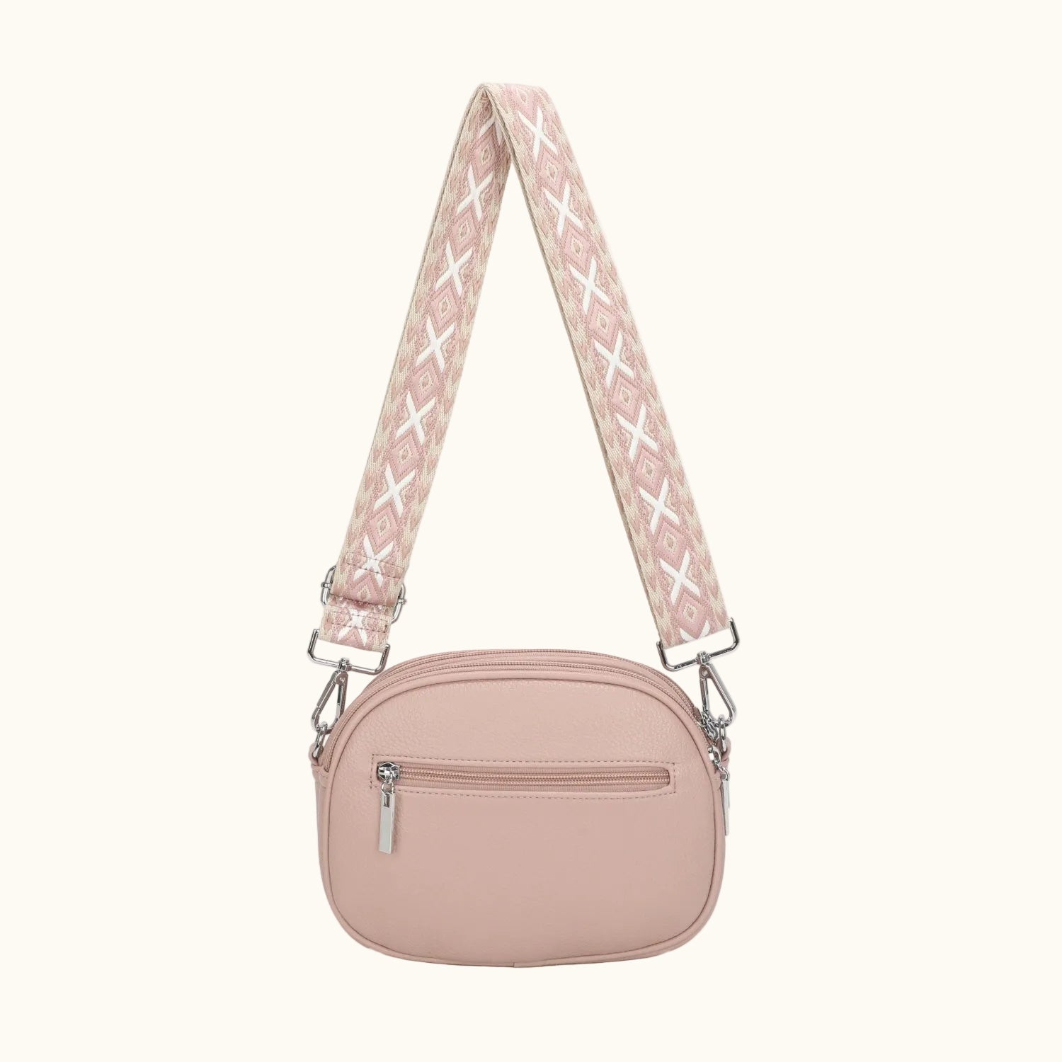 Pink crossbody bag with a patterned strap on a white background