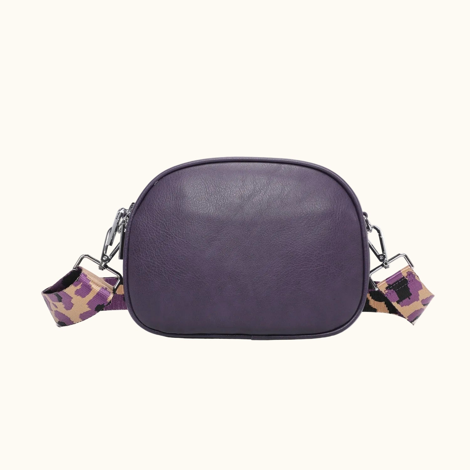 Purple leather crossbody bag with patterned straps on a white background