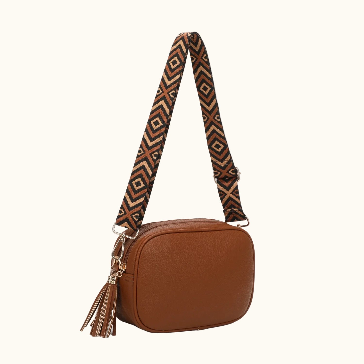 Brown leather crossbody bag with a patterned strap on a white background