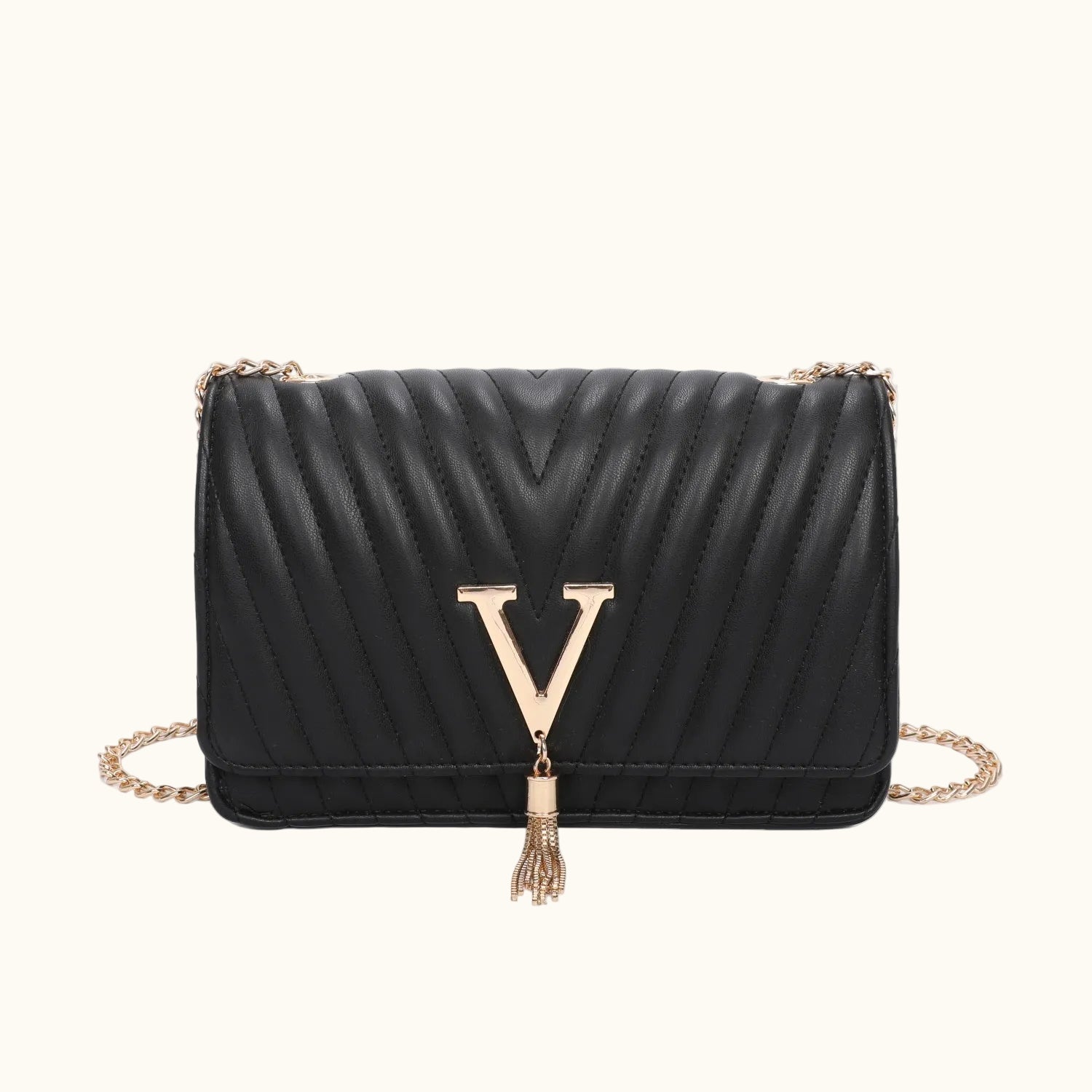 Black quilted handbag with gold chain and tassel on a white background