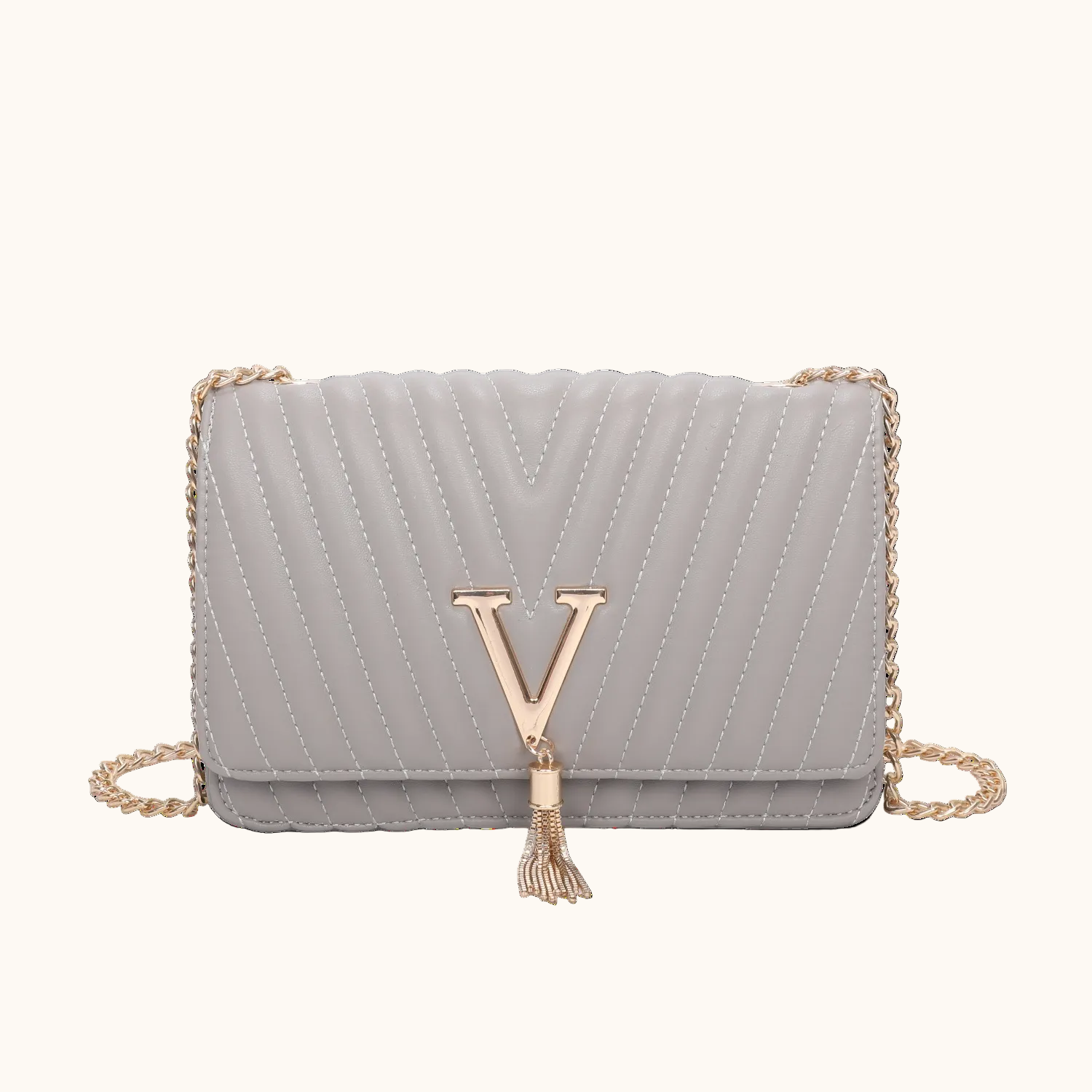 Gray quilted handbag with gold chain and tassel on a white background
