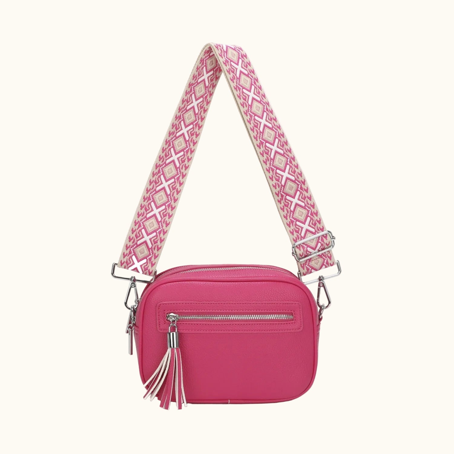 Pink crossbody bag with a patterned strap on a white background