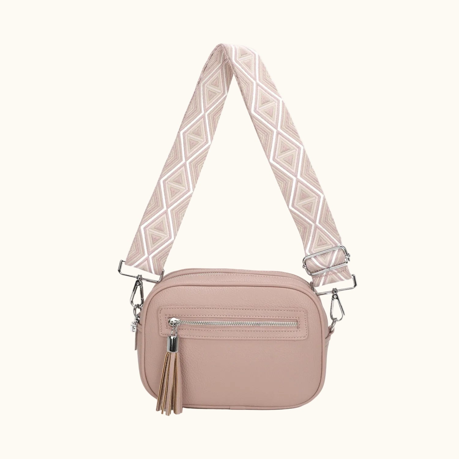 Pink crossbody bag with a patterned strap on a white background