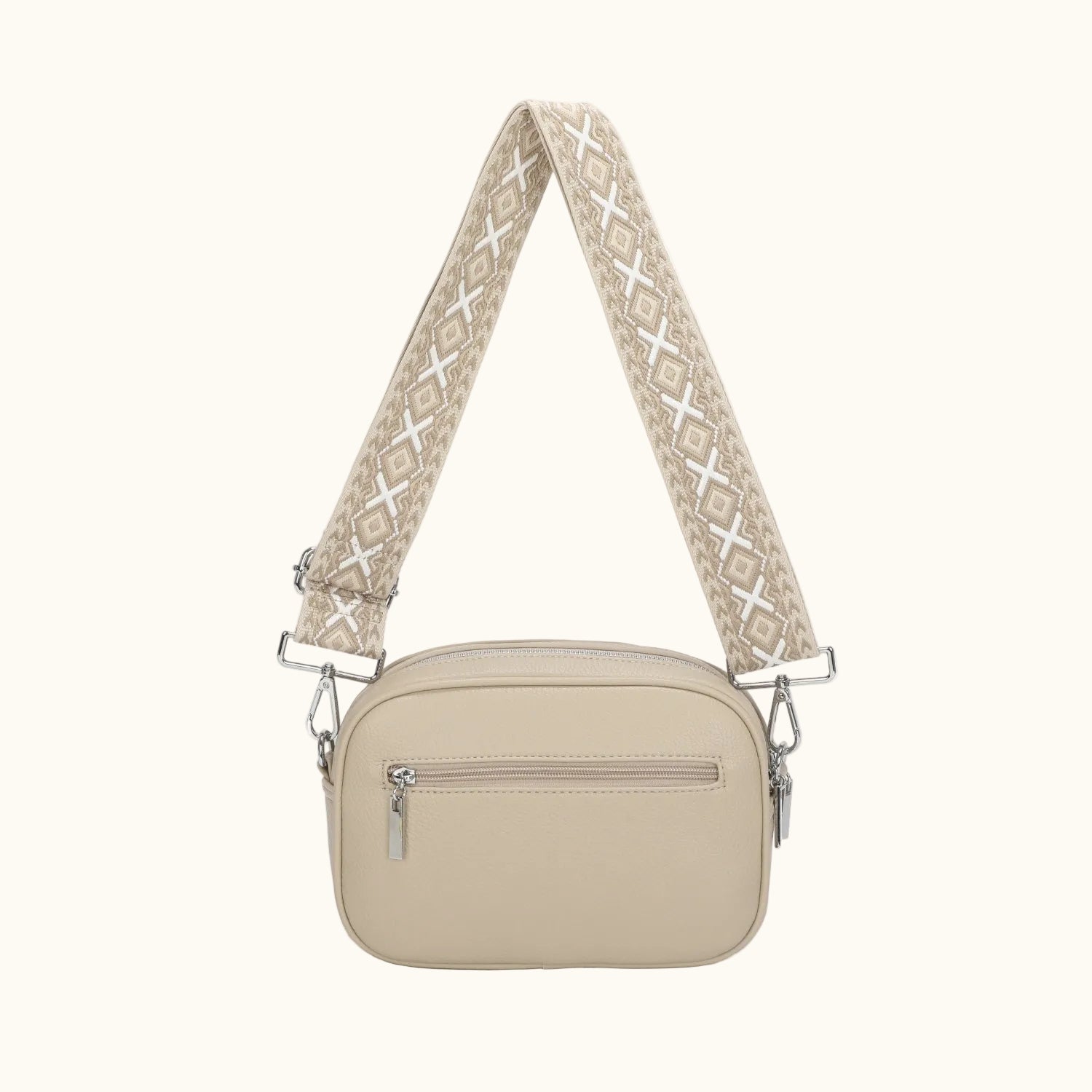 Beige crossbody bag with a patterned strap on a white background