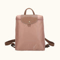 Pink backpack with brown leather accents on a white background