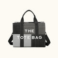 Gray tote bag with black handles and a visible brand name on a white background