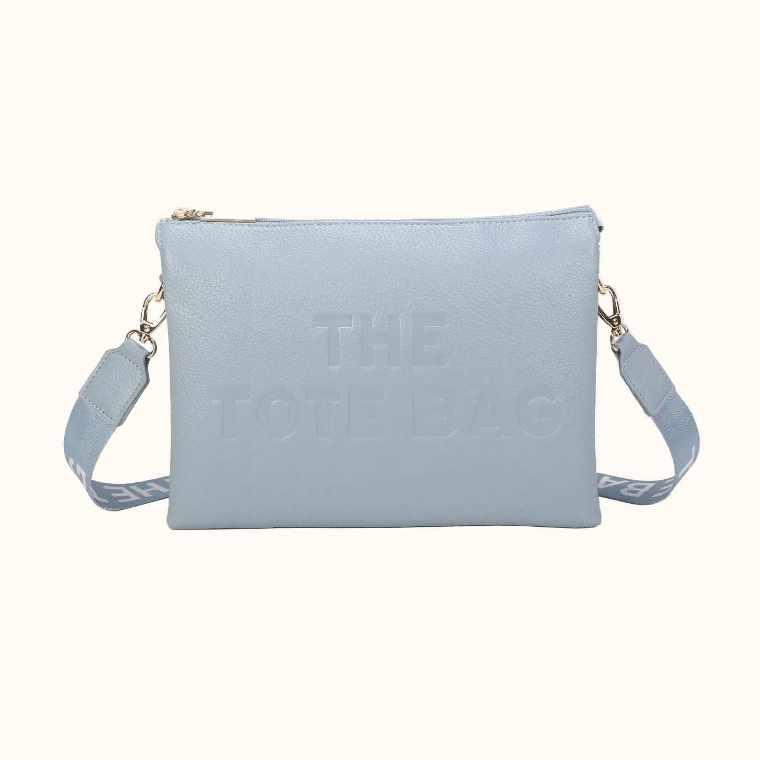 Light blue crossbody bag with 'THE TOTE BAG' text on a white background