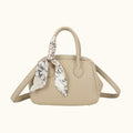 Beige handbag with a patterned scarf on a white background