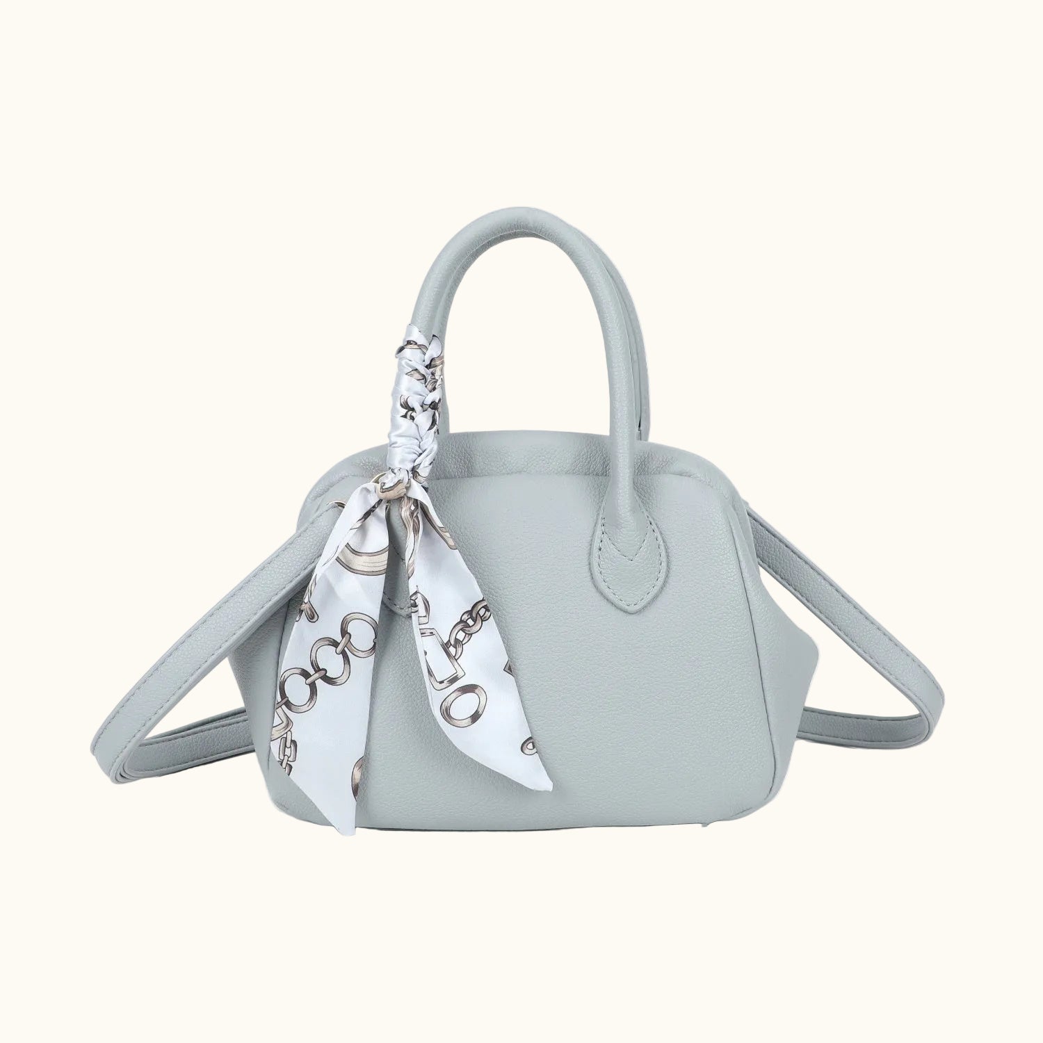 Light blue handbag with a white scarf tied around the handle on a white background