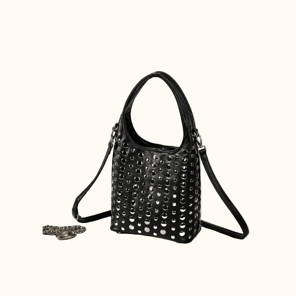 Black studded handbag on a gray surface with a neutral background
