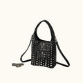 Black studded handbag on a gray surface with a neutral background
