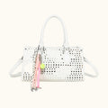 White perforated handbag with a pink and green charm on a white background