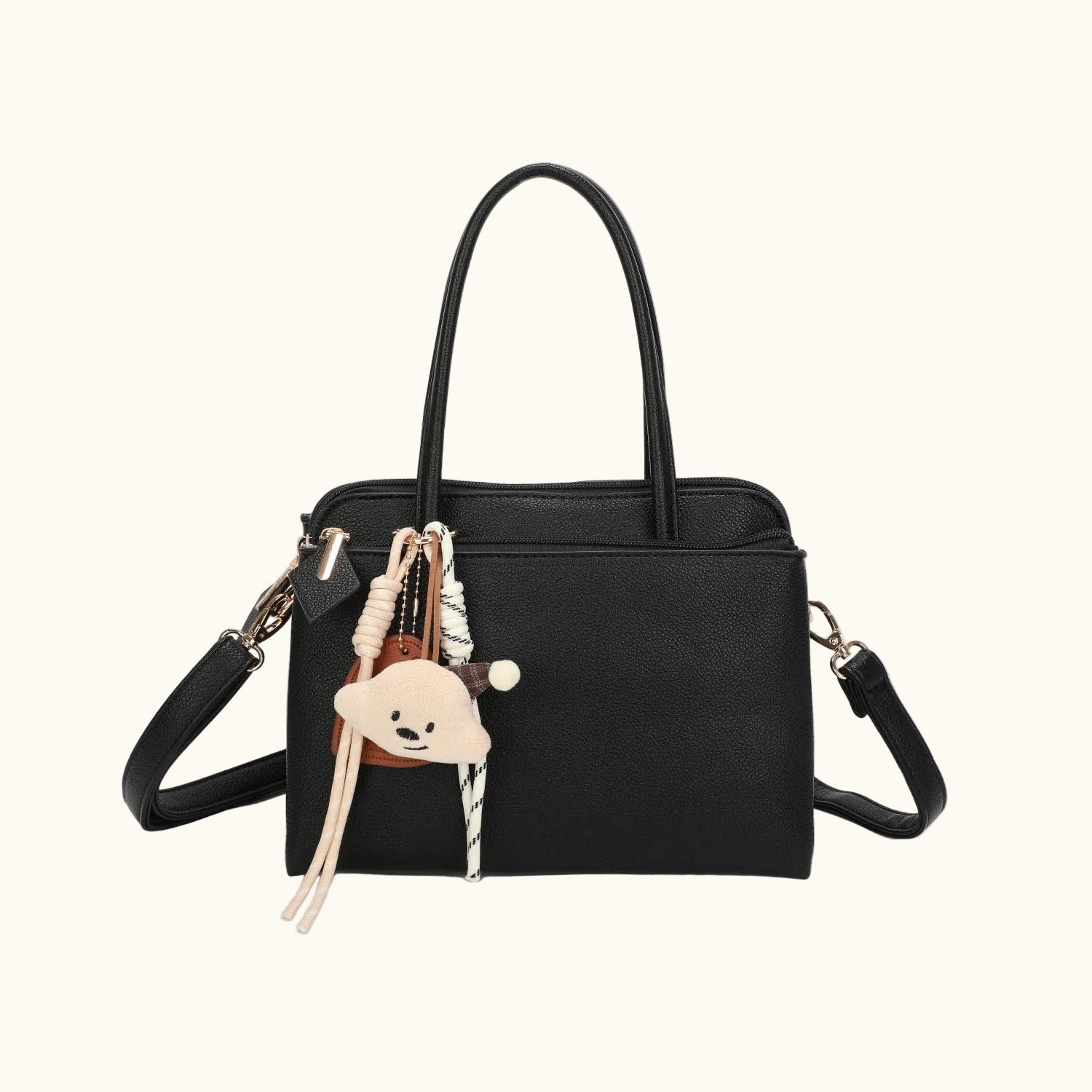 Black handbag with a teddy bear keychain on a white background