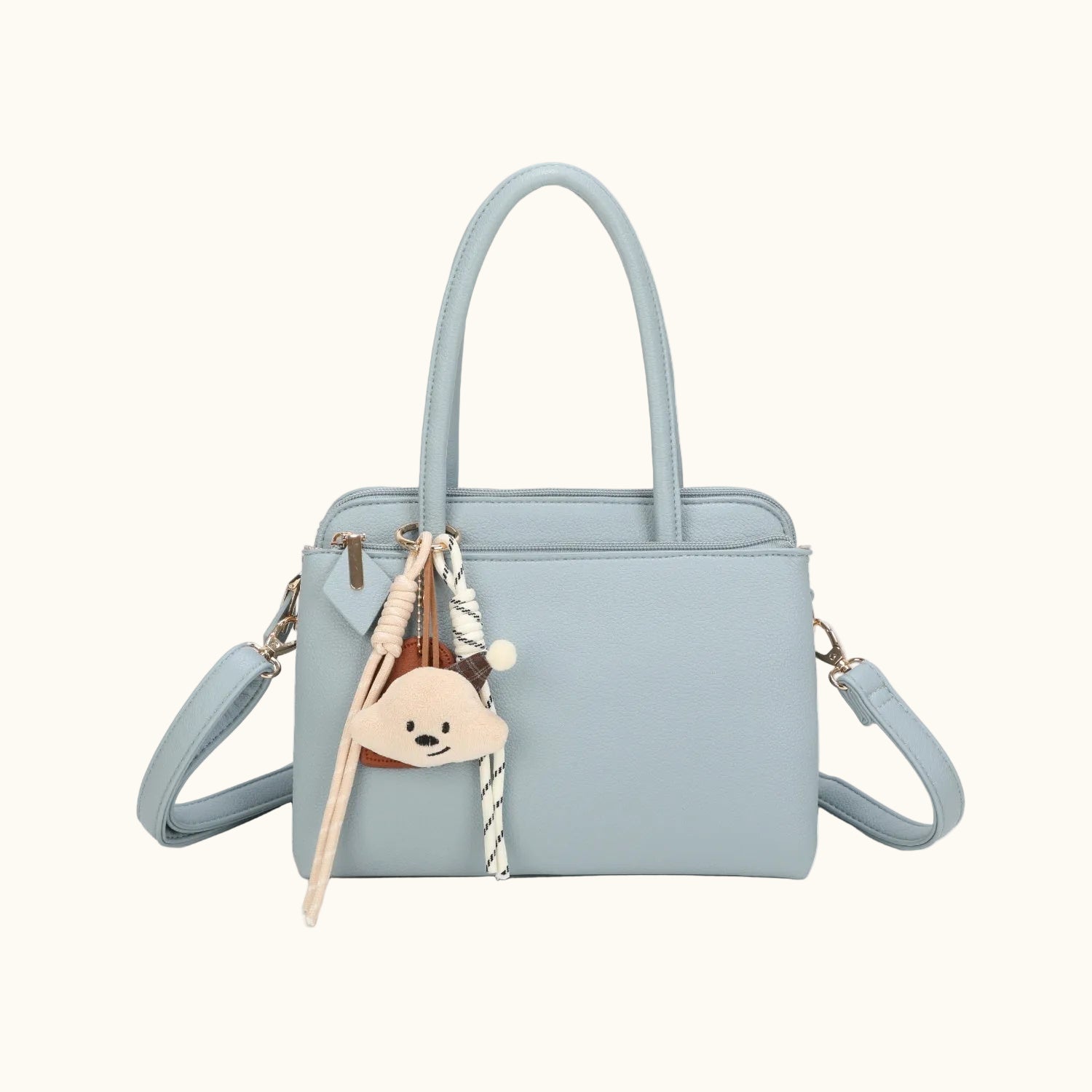 Light blue handbag with a teddy bear keychain on a white background