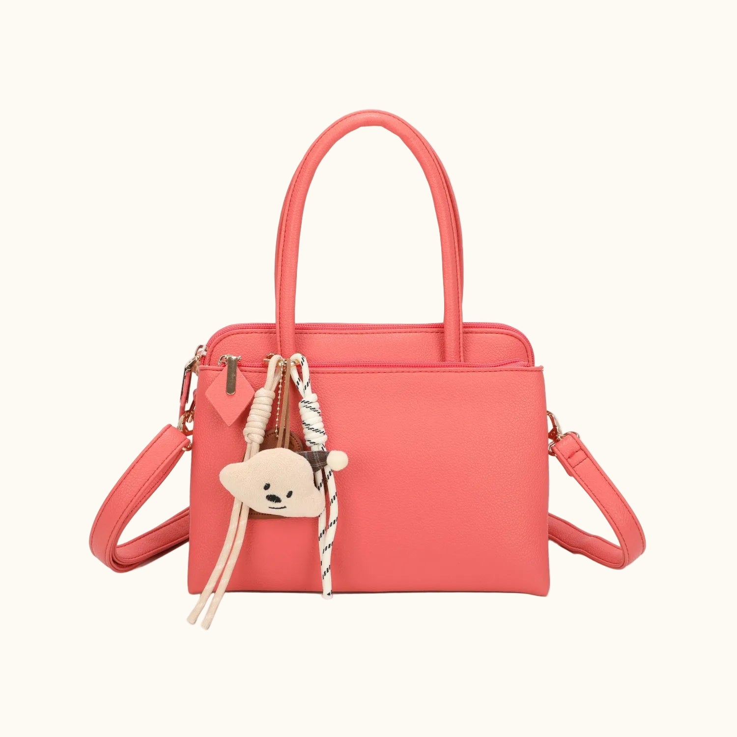 Coral handbag with a teddy bear charm on a white background