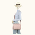 Mannequin wearing a light blue outfit with a pink handbag and white hat on a white background