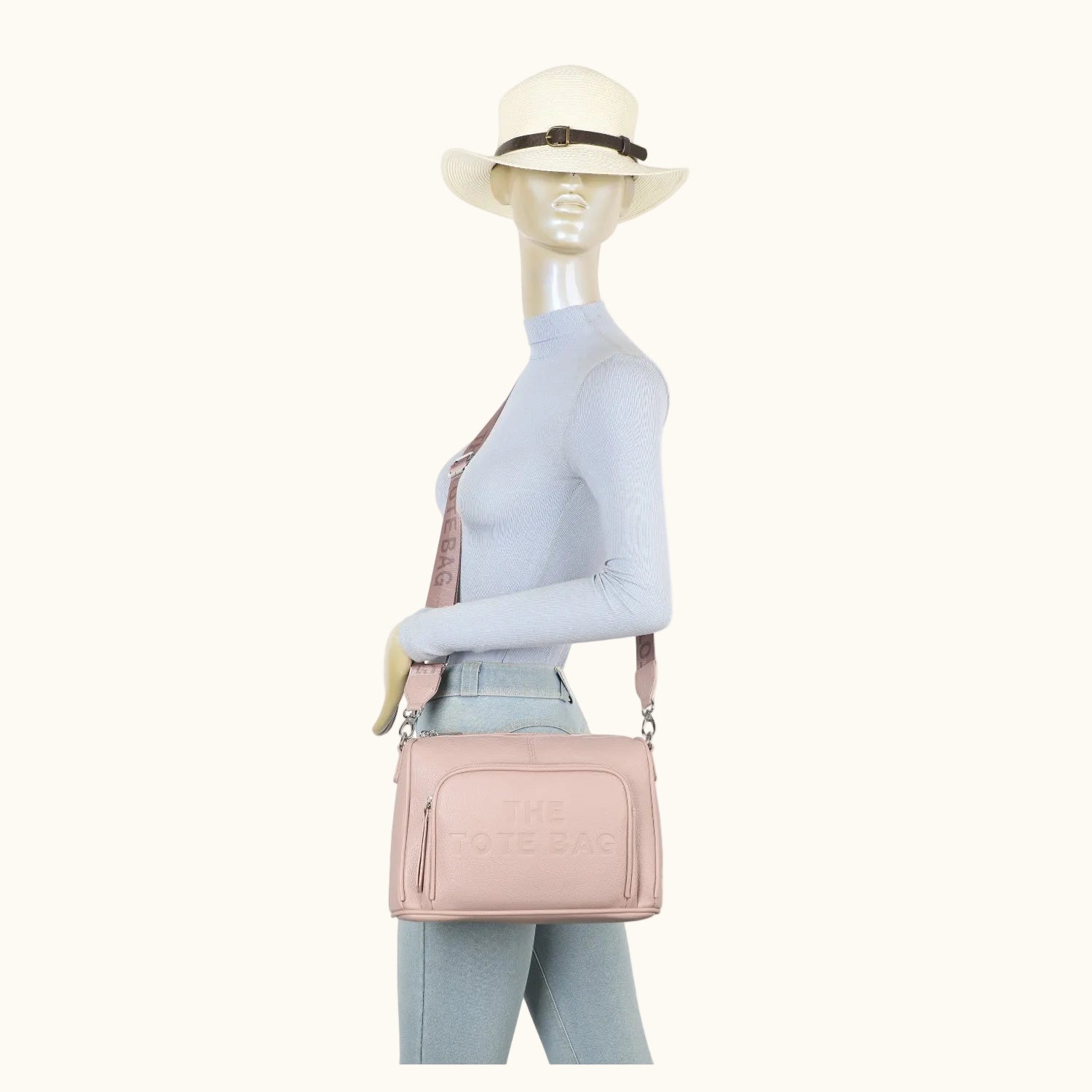 Mannequin wearing a light blue outfit with a pink handbag and white hat on a white background