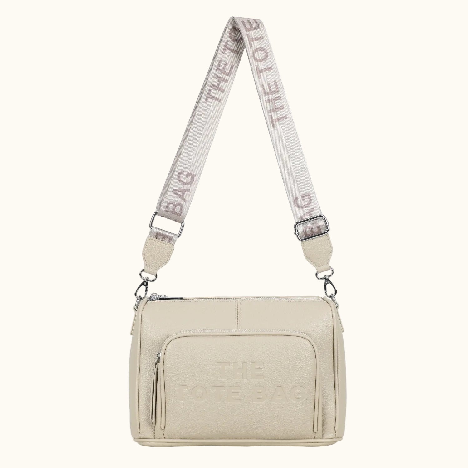 Beige handbag with 'The Tote Bag' strap on a white background