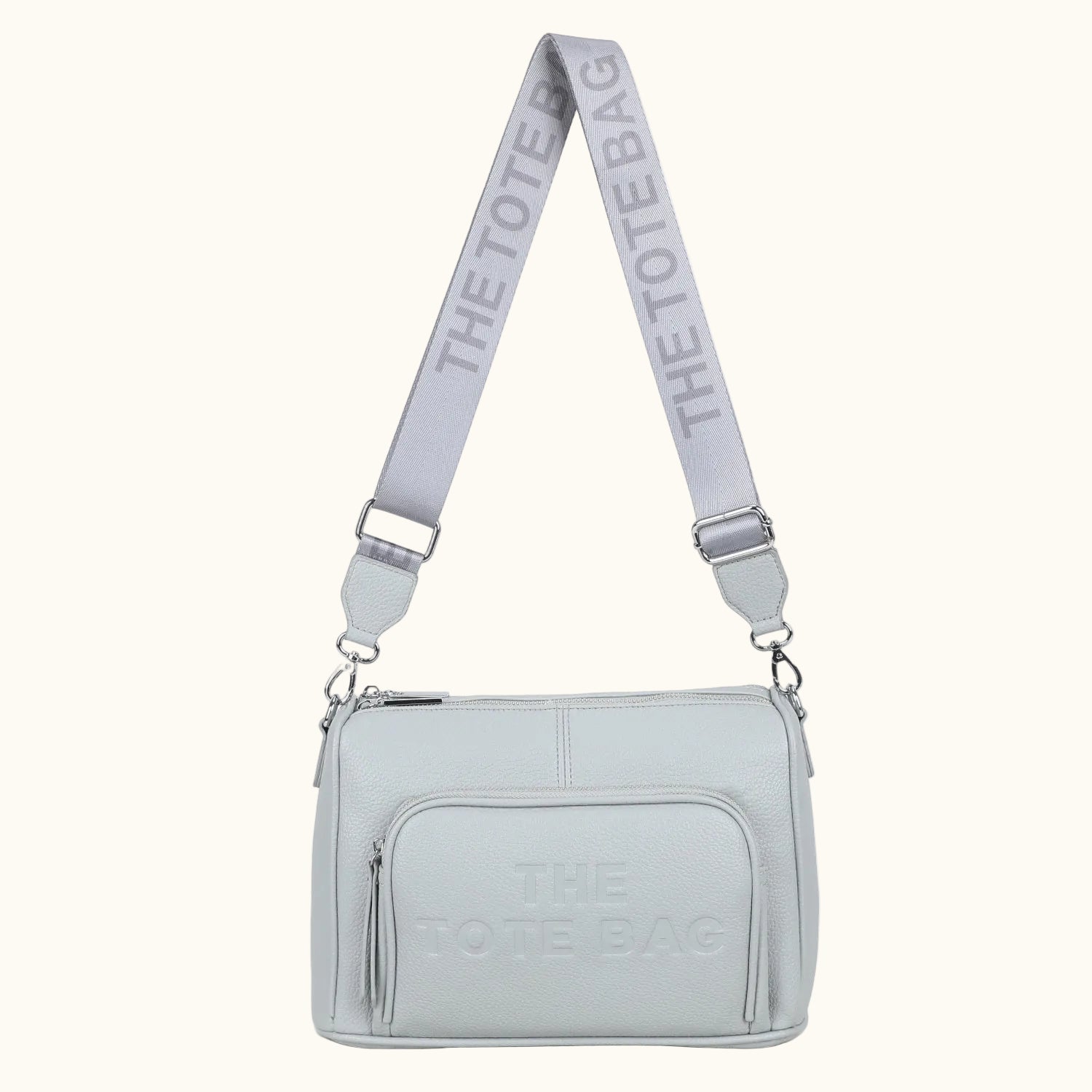 Light gray crossbody bag with 'The Tote Bag' branding on a white background