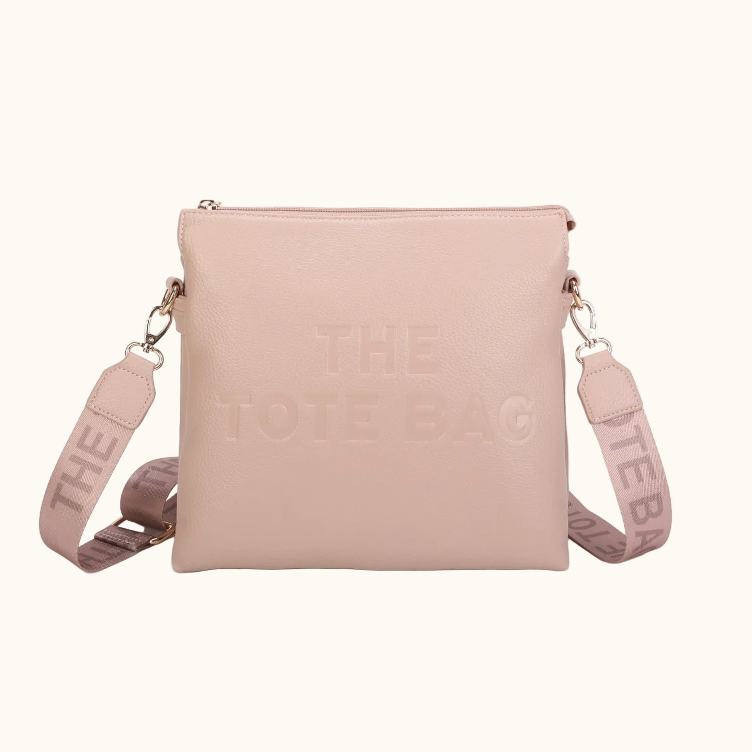 Pink crossbody bag with 'THE TOTE BAG' text on a white background
