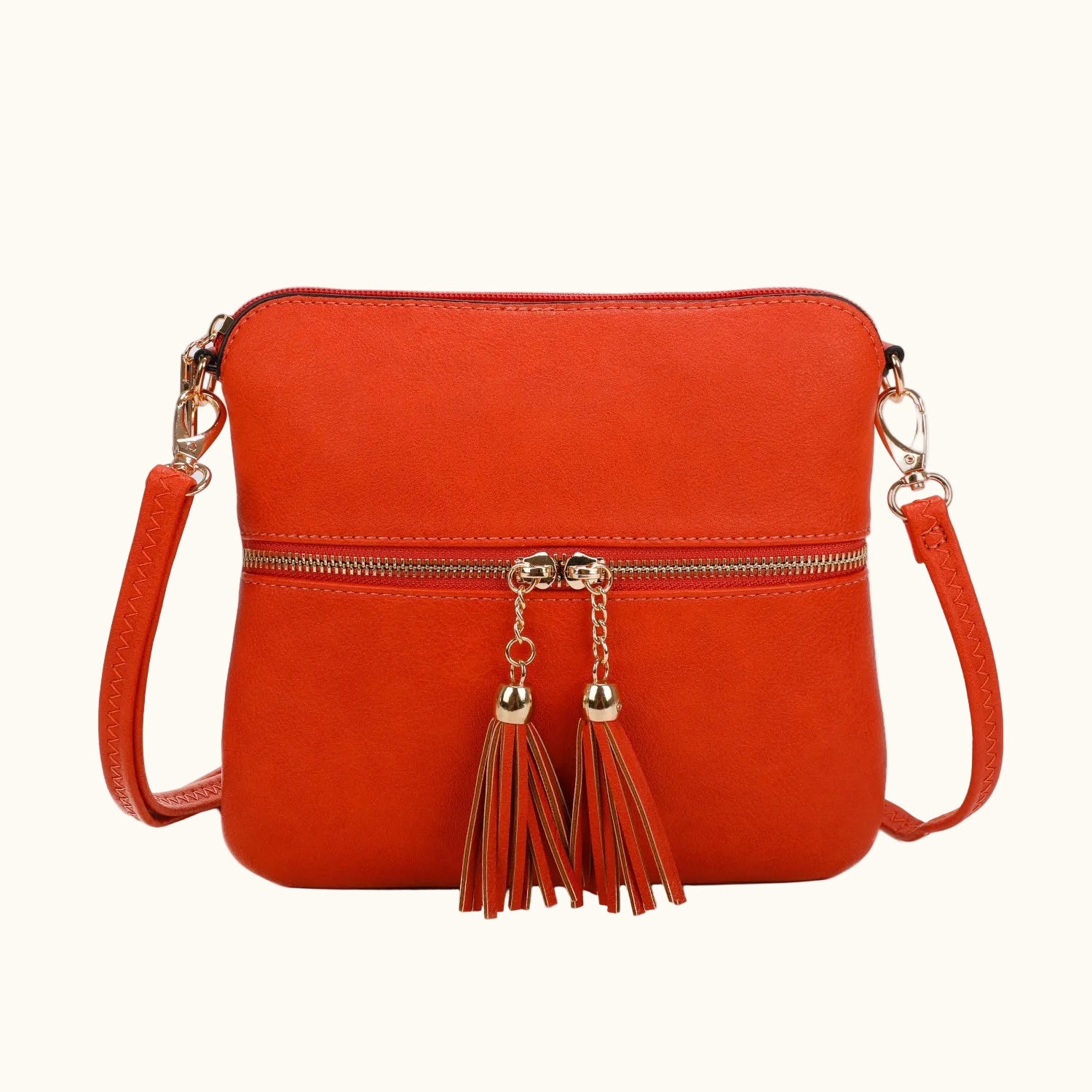 Orange crossbody bag with gold tassels on a white background