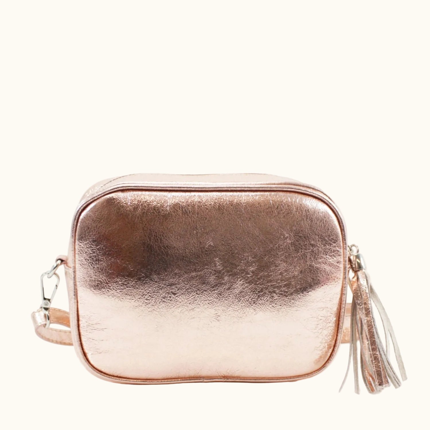 Rose gold crossbody bag with tassel on a white background